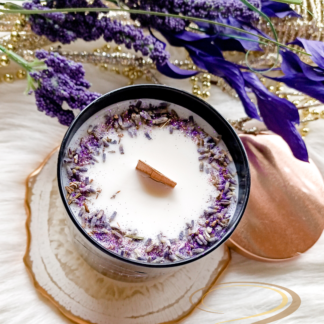 Lavender Fields soy candle in a black glossy tumbler jar, featuring a wooden wick and decorated with real dried lavender buds and soft purple botanicals.