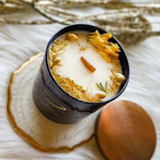 Jasmine Honeysuckle soy candle in a black glossy tumbler jar, featuring a wooden wick and decorated with vivid yellow botanicals, dried grasses, and jasmine buds.