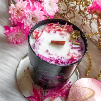 Blossom Musk soy candle in a black glossy tumbler jar, decorated with pink dried flowers and botanicals, featuring a wooden wick